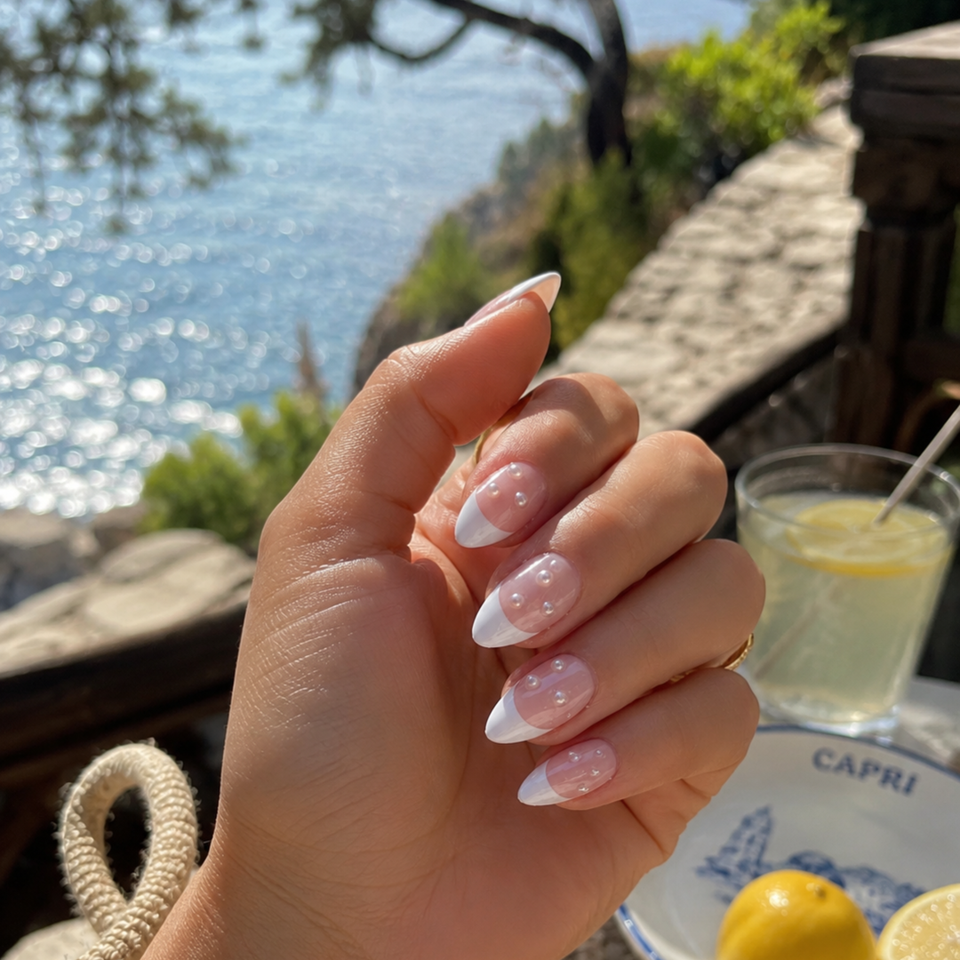 Hand with press on nails by a scenic waterfront